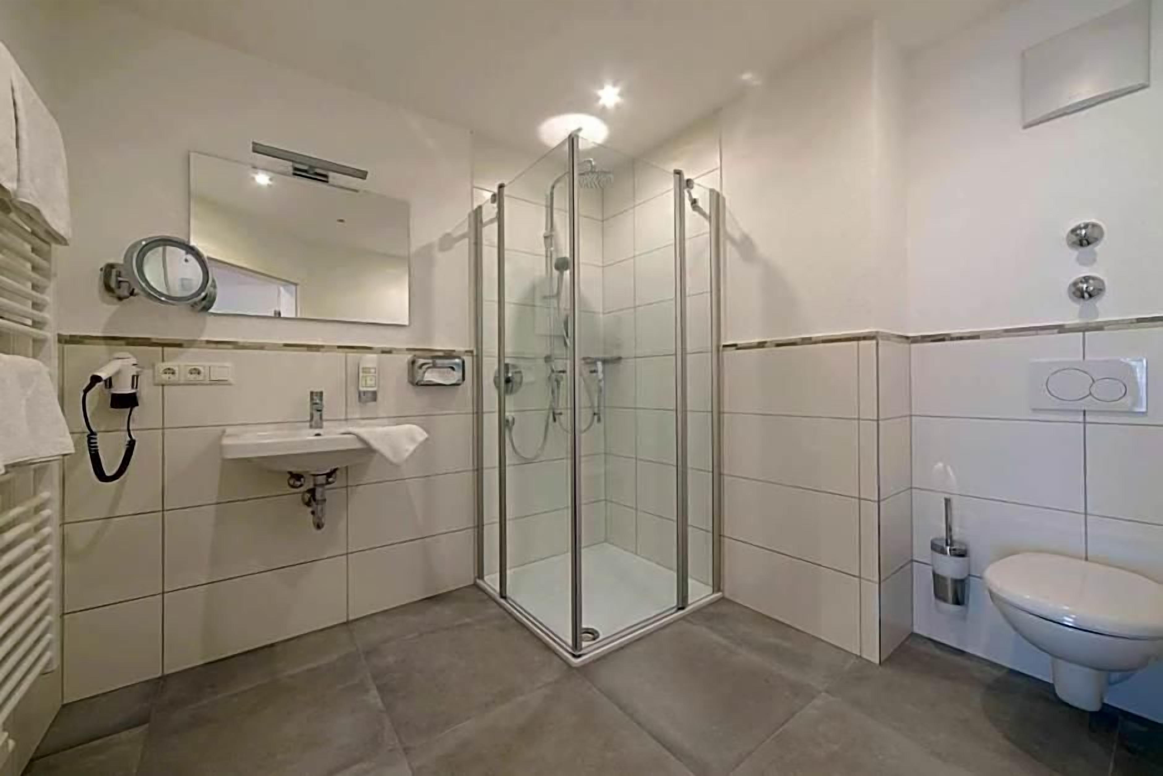 Une salle de bain moderne avec une douche à parois de verre, un lavabo et des toilettes.
