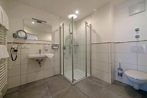Et moderne badeværelse med brusekabine i glas, vask og toilet.