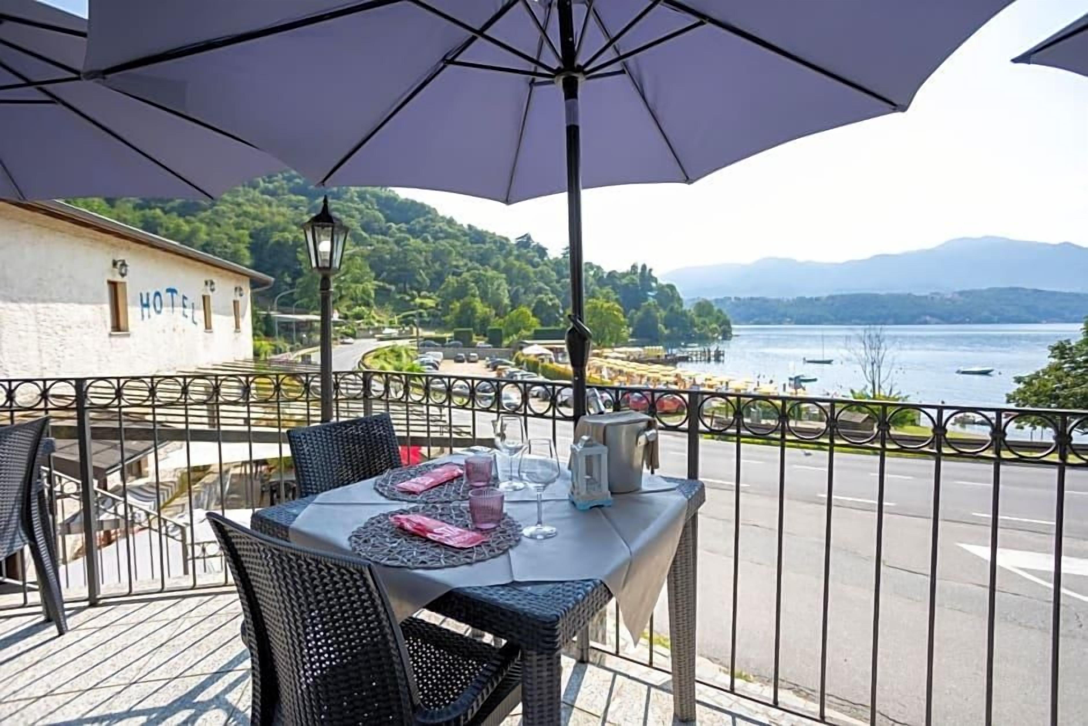 A terrace with a table set for dining, overlooking a lake and mountains.
