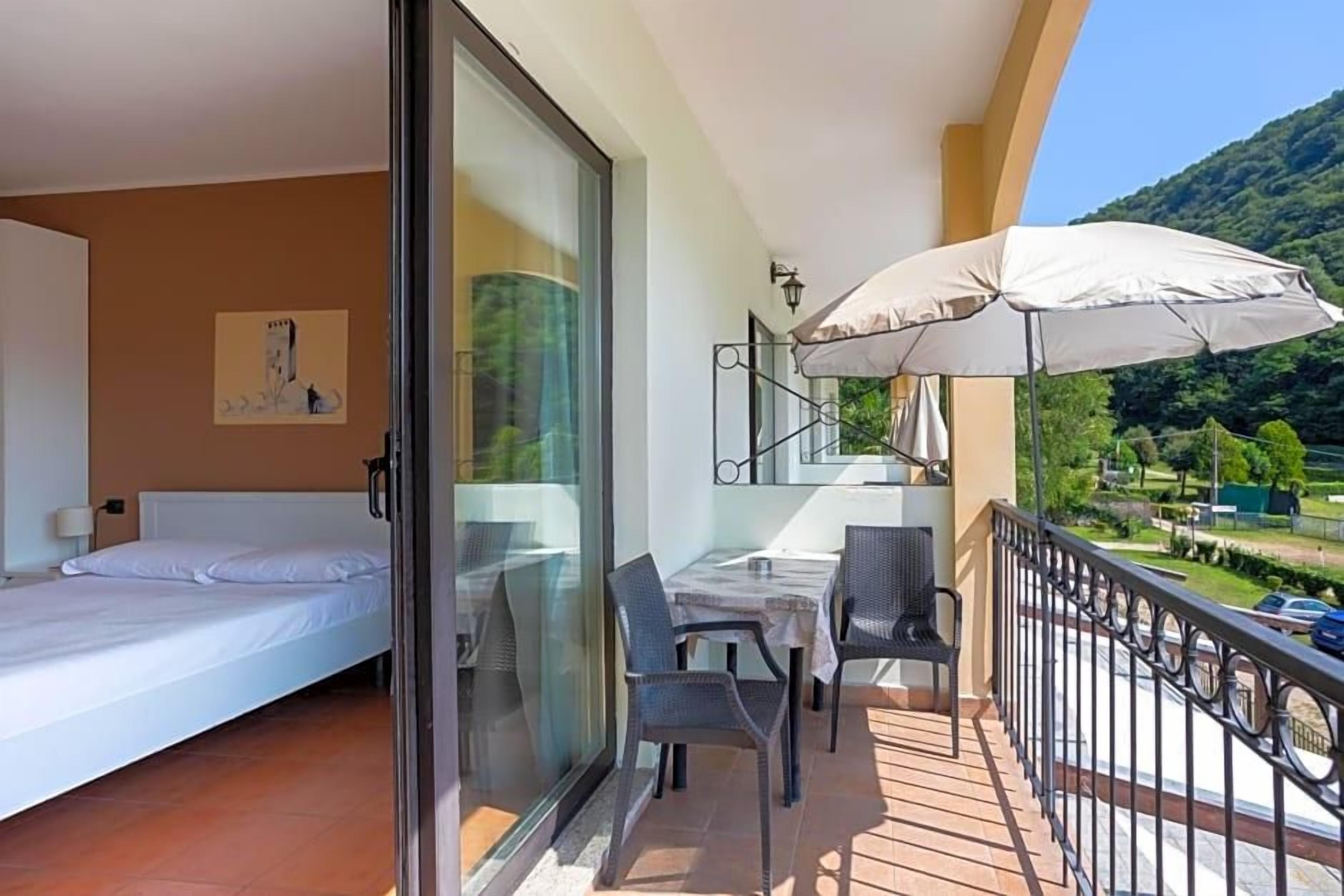 A balcony with a table, chairs, and a large umbrella.
