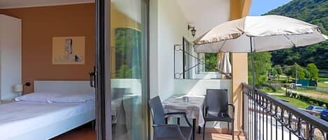 A balcony with a table, chairs, and a large umbrella.