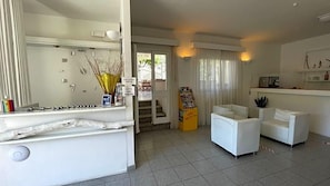 A hotel room with a large mirror, a white sofa, a small table, and a view of the outside. - Hotel L'ogliera (Marciana)