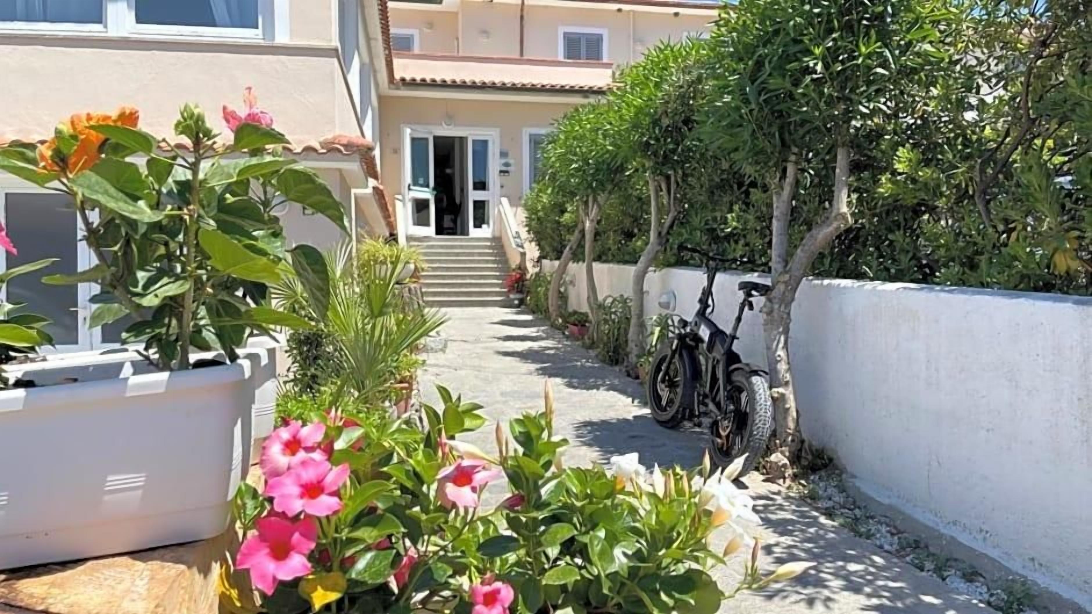 A pathway leading to a building with a white exterior and a bicycle parked by the side.