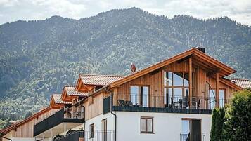 Ein mehrstöckiges Holzhaus mit Balkonen vor einer Bergkulisse.