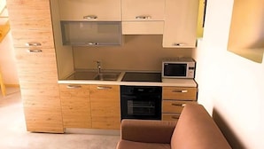 Een kleine keuken met een magnetron, oven en spoelbak.