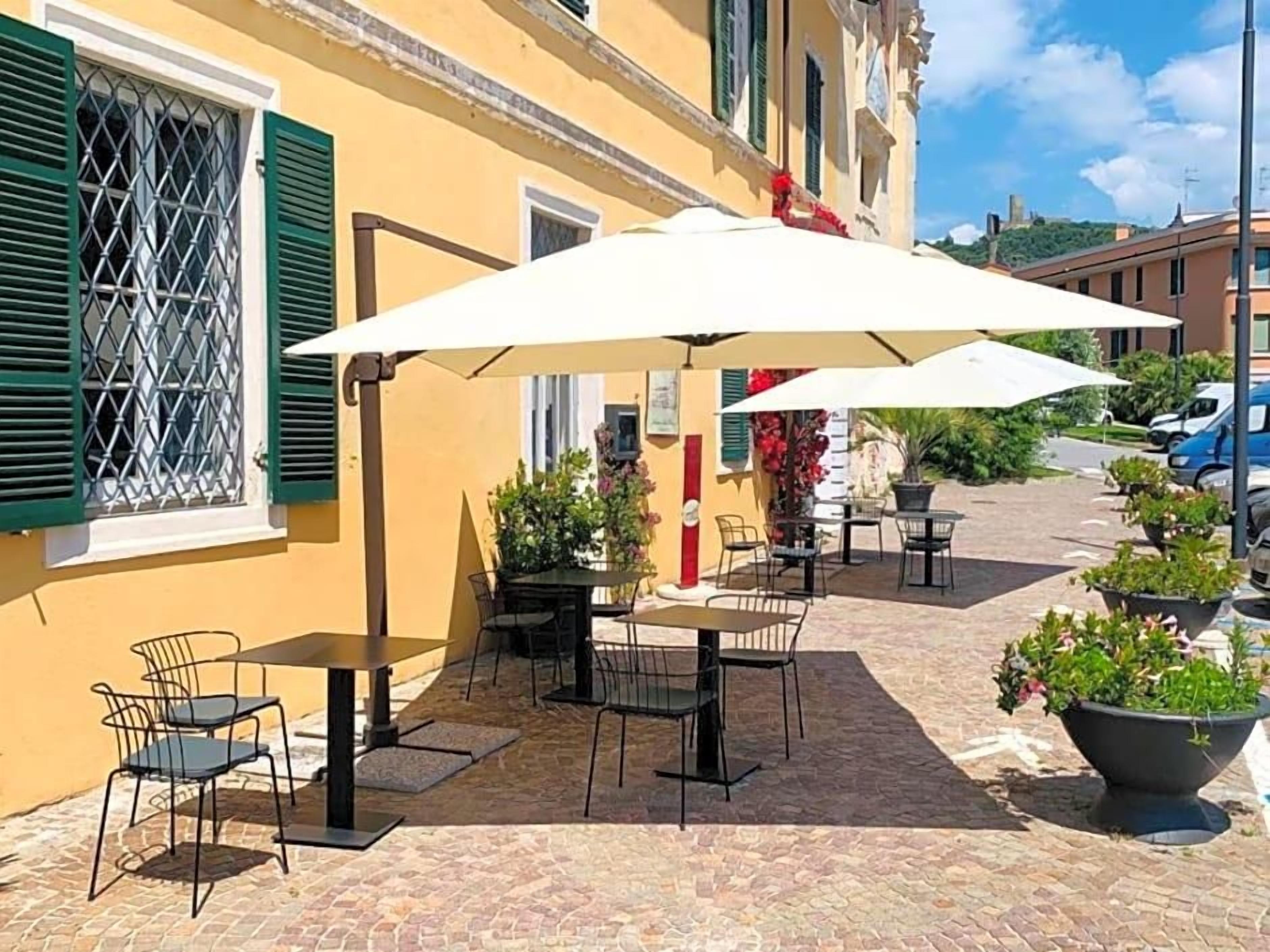 Een terras met tafels, stoelen, parasols en potplanten.