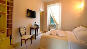 Een hotelkamer met een bed, een stoel, een bureau, een televisietoestel en een kledingkast.