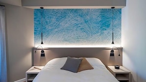 A bedroom with a bed, two bedside tables, and a wall-mounted light fixture. - Comfort Zone (Codroipo)
