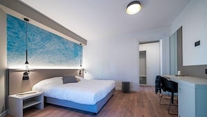 A modern bedroom with a large bed, bedside tables, a desk, and a chair. - Comfort Zone (Codroipo)