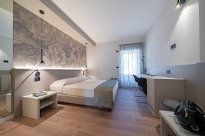 Ett modernt hotellrum med en säng, ett skrivbord och en stor väggmålning.