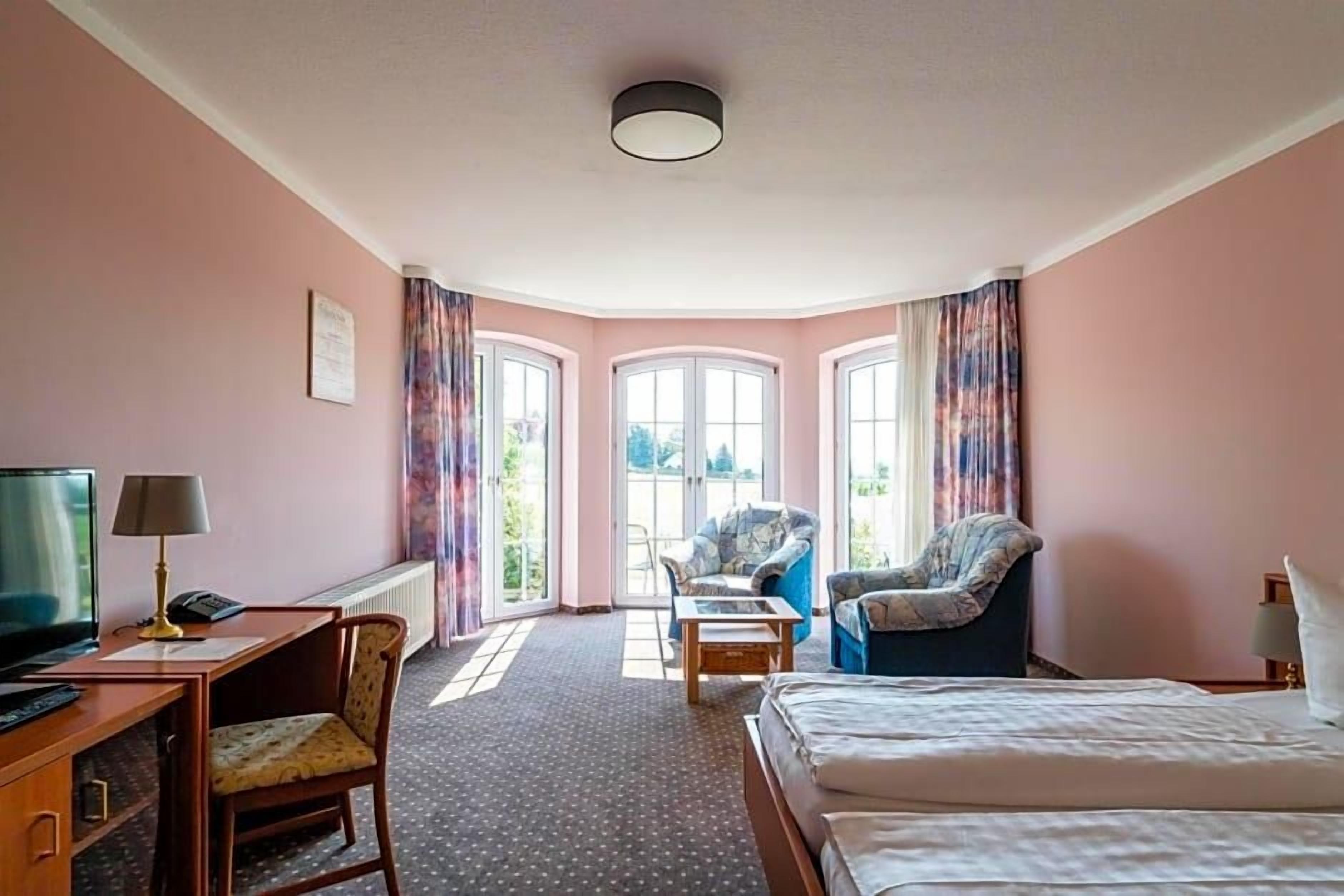 Ein Hotelzimmer mit Bett, Schreibtisch, Stuhl und Blick aus dem Fenster.