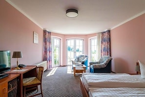 A hotel room with a bed, desk, chair, and a view through the window. - Hotel Marianne Und Restaurant Kiek In (Plau am See)