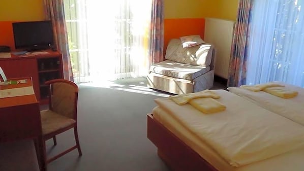 A hotel room with a bed, a desk, a chair, and a television. - Hotel Marianne Und Restaurant Kiek In (Plau am See)