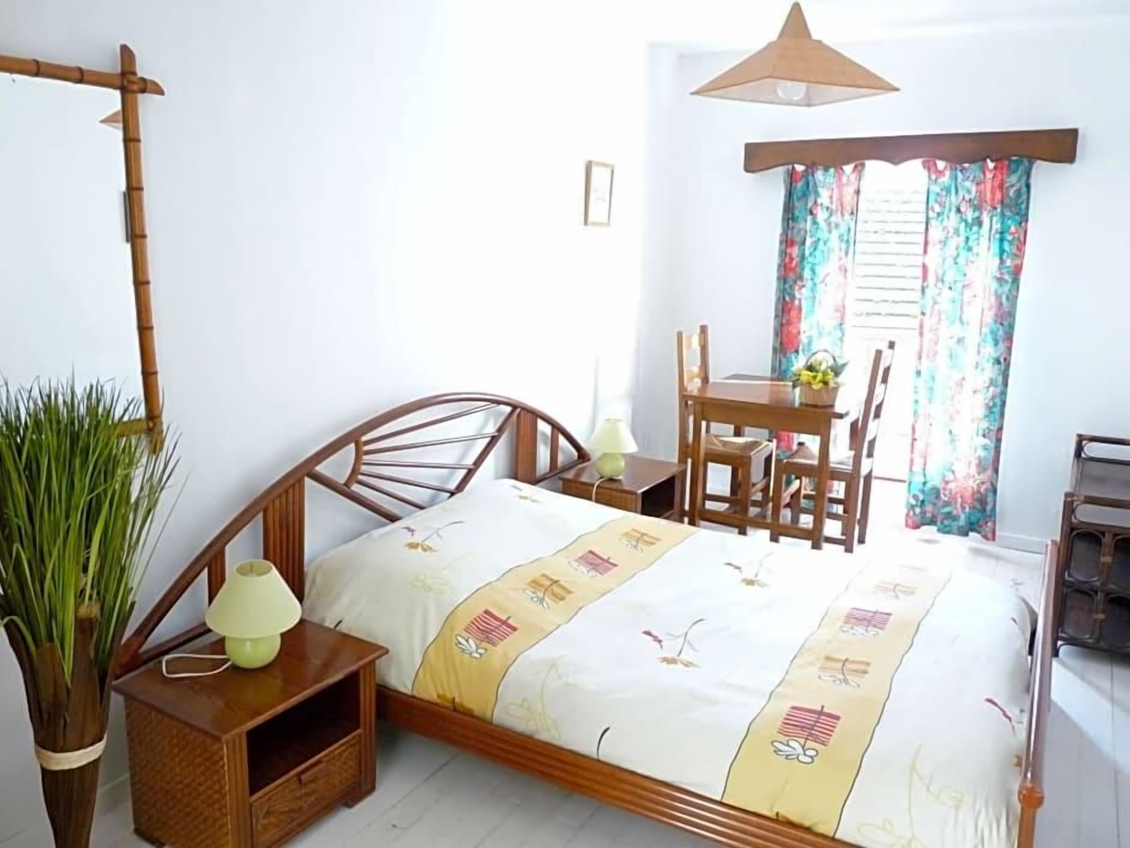 Un dormitorio con una cama de madera, mesitas de noche, un escritorio y una silla.