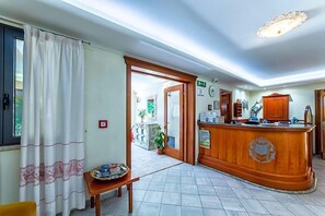 Uma área de recepção com balcão de madeira, um balcão com cesto e uma porta que dá para outro espaço.