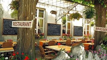 Un restaurant en plein air, avec des tables et des chaises, entouré d’arbres et de fleurs.