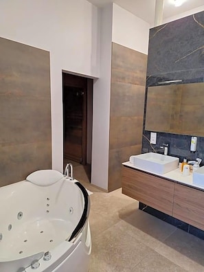 A modern bathroom with a freestanding bathtub, a vanity with a mirror, and a large mirror above the sink.
