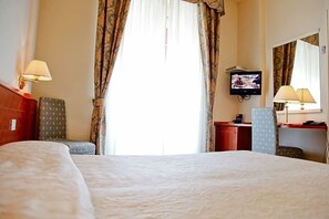 A hotel room with a large bed, a desk, a television, and a chair. - Hotel Cristallo (Fano)