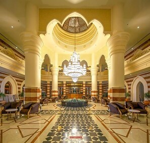 A lobby with a central fountain, seating areas, and a chandelier. - Grand Palace Adults Only 18 Years Plus (Hurghada)