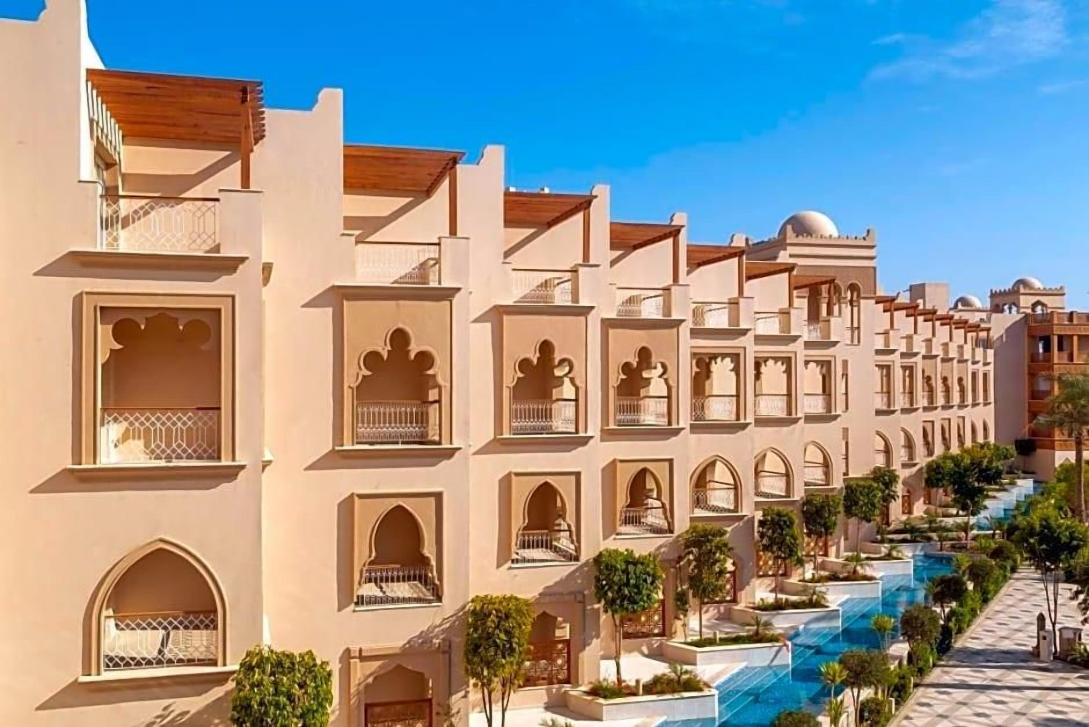 Un hotel con varios balcones, una piscina y cielo despejado.
