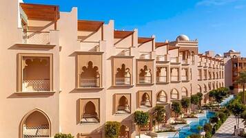 Un hotel con varios balcones, una piscina y cielo despejado.