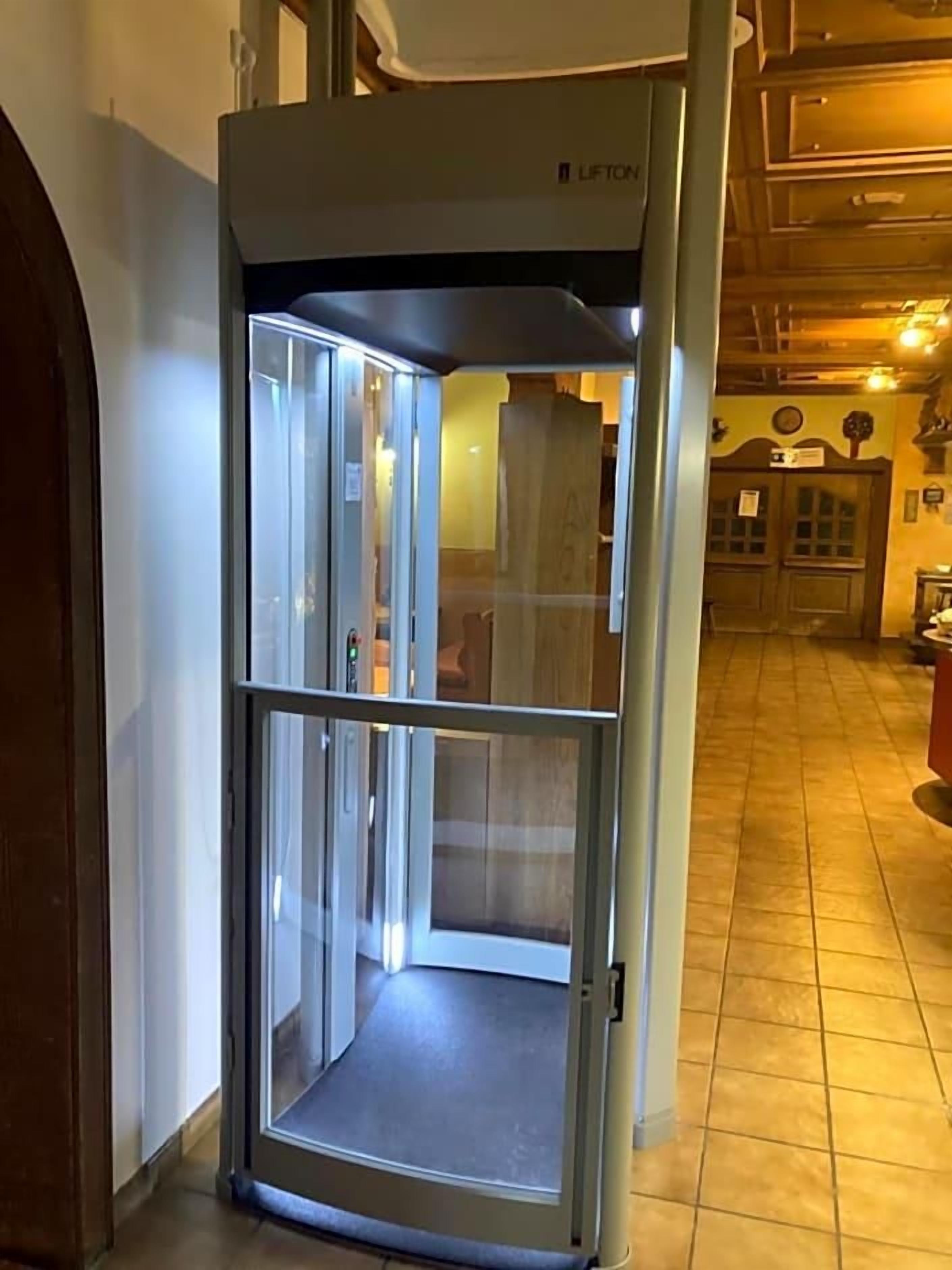 Un ascensor con cabina de vidrio en un pasillo.