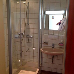A bathroom with a glass-enclosed shower, a sink, and a mirror. - Hotel Sonnenhof (Thannhausen)