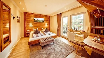Un dormitorio con panel de pared de madera, una cama con almohadas, un banco, una ventana con cortinas y una mesa con bandeja.