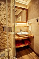 Un baño moderno con cabina de ducha de vidrio, tocador de madera y un espejo grande.