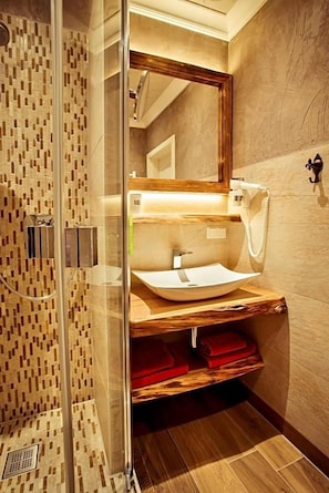 Un baño moderno con cabina de ducha de vidrio, tocador de madera y un espejo grande.