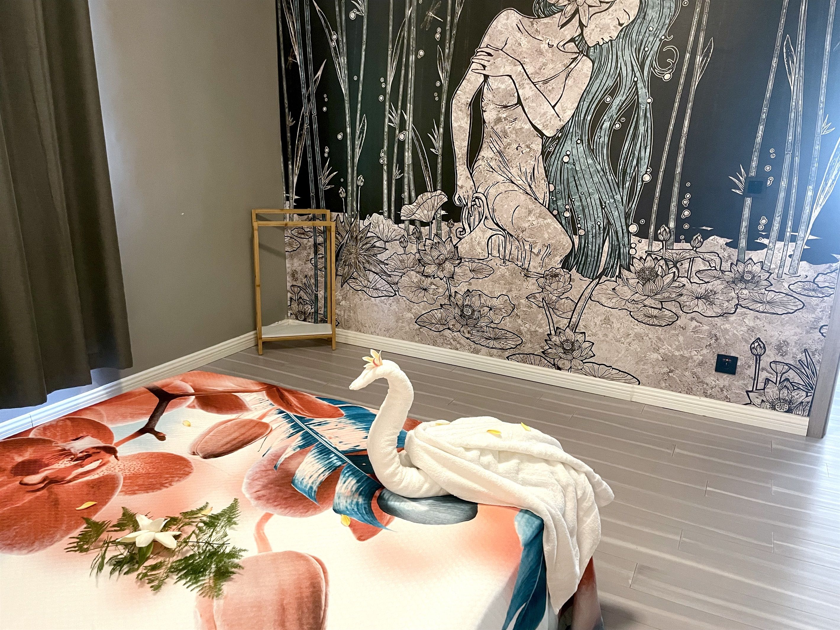 Une pièce ornée d’une grande fresque murale, avec une chaise en bois et un cygne décoratif posé sur une table.
