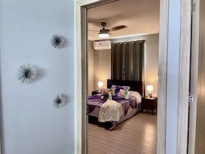 Ein Schlafzimmer mit Bett, Nachttischen, Deckenventilator und dekorativen Wandbildern.