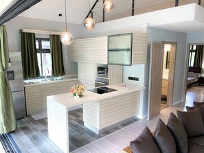 A modern kitchen with a central island, a dining area with a sofa, and a living room with a TV. - Fare Luna - Comfy New Home in Bora Bora (Bora-Bora)