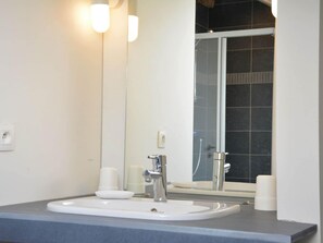 A bathroom with a white sink, a mirror, and a shower visible through the glass door. - Beautiful Ardennes House In Quiet Area (Sainte-Ode)