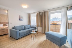 Sala de estar moderna com sofá, uma mesinha com copos e uma garrafa de água, e vista para uma montanha através de amplas janelas.