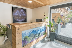 Un mostrador de recepción de hotel con un logotipo grande enmarco, una pantalla digital y vistas al exterior.