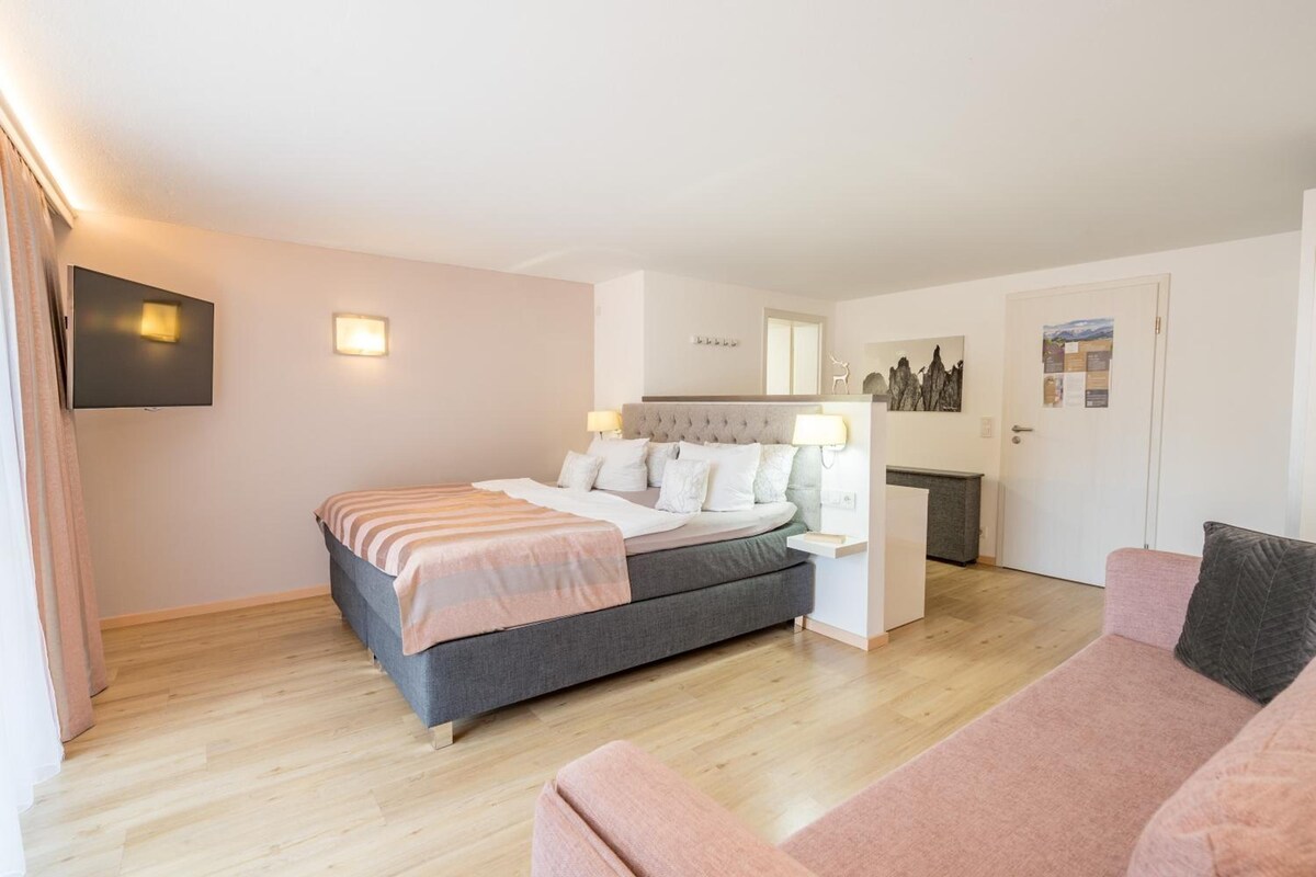 Um quarto com cama, mesa de cabeceira e criado-mudo.