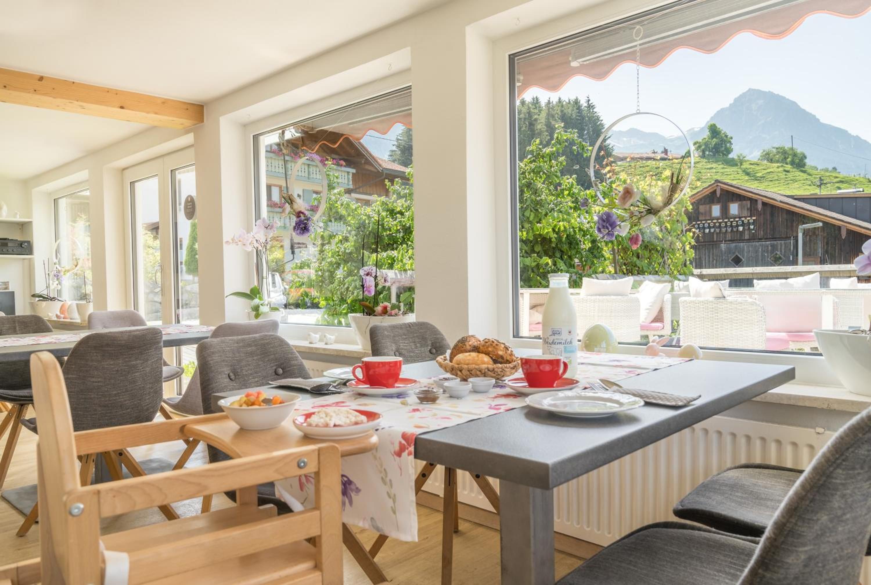 Ein Essbereich mit einem Tisch für zwei Personen, Stühlen und Blick auf eine Berglandschaft.