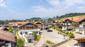 Un hotel con un cartel que dice 'Bichl 761 Alpin-Hotel' en un entorno rural, con estacionamiento y casas aledañas.