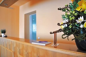 Un comptoir d’accueil avec une plante en pot, un stylo et un bloc-notes.
