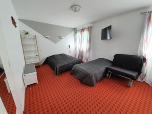A compact room with two beds, a desk, a chair, a TV, and a window with curtains. - Hotel De La Poste (Espinasses)