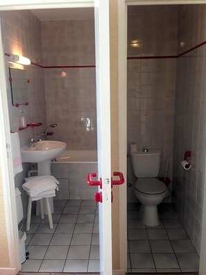 A bathroom with a white sink, a bathtub, and a toilet. - Hotel De La Poste (Espinasses)