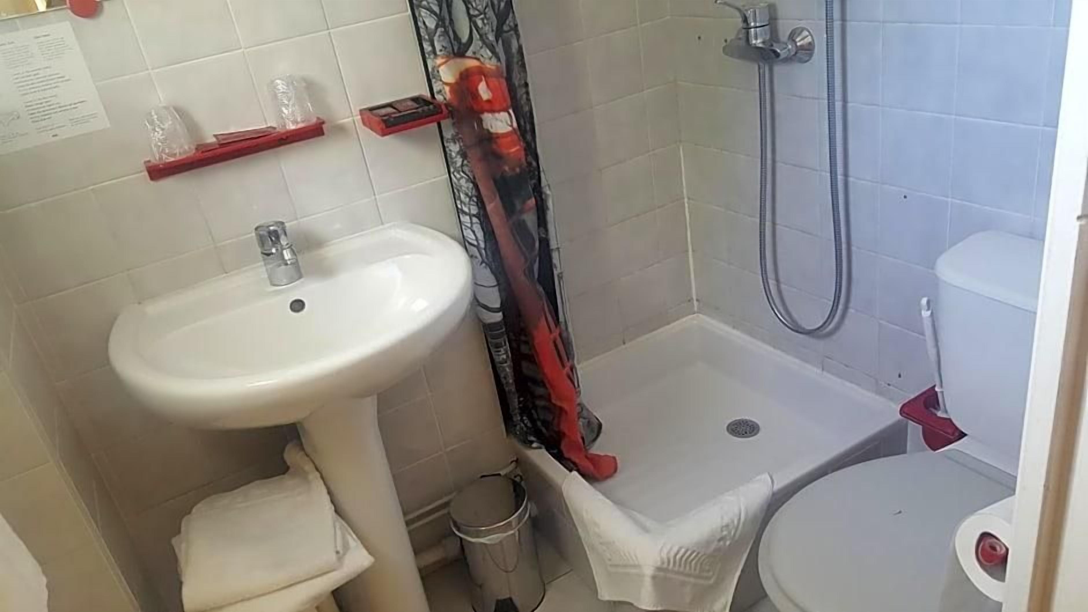 Une salle de bain équipée d’un lavabo, de toilettes, d’une douche et d’une poubelle.