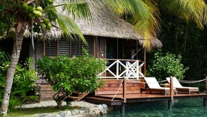A thatched-roof structure with a wooden deck, lounge chairs, and a pool. - Hotel Central Bocas Del Toro (Panama)