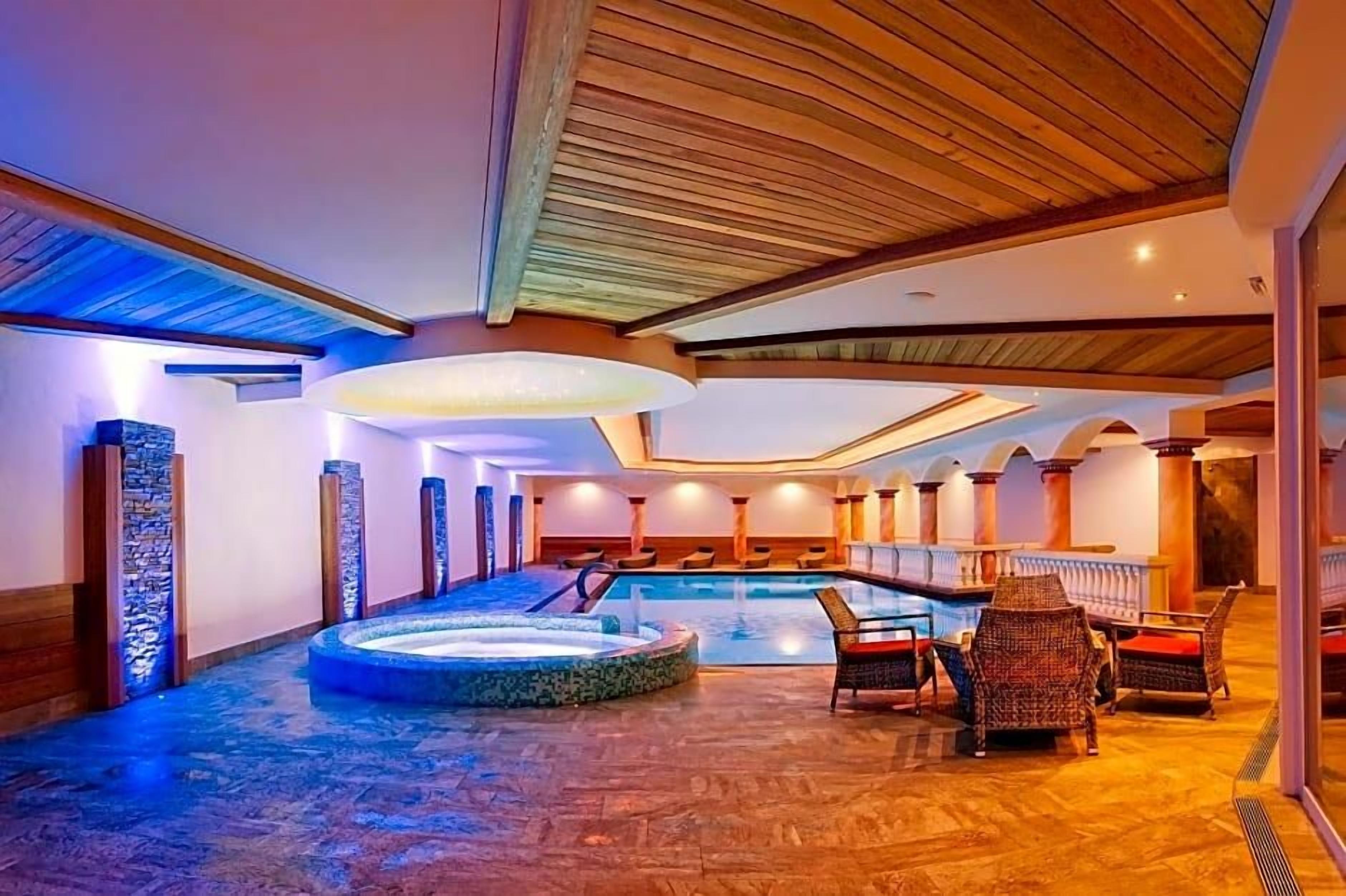 A spa area with a hot tub, seating, and a pool.