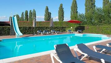 Ein Schwimmbecken mit Liegestühlen und einer Rutsche.