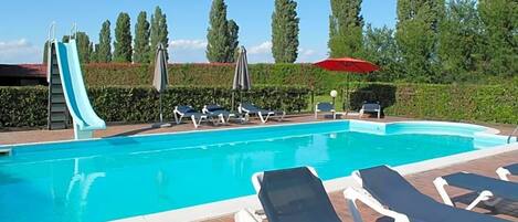 A swimming pool with lounge chairs and a slide.