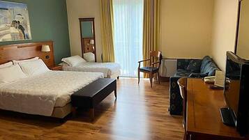 Ein Hotelzimmer mit zwei Betten, einem Schreibtisch mit Telefon, einem Stuhl und einem fensterbepflanzten Fenster.