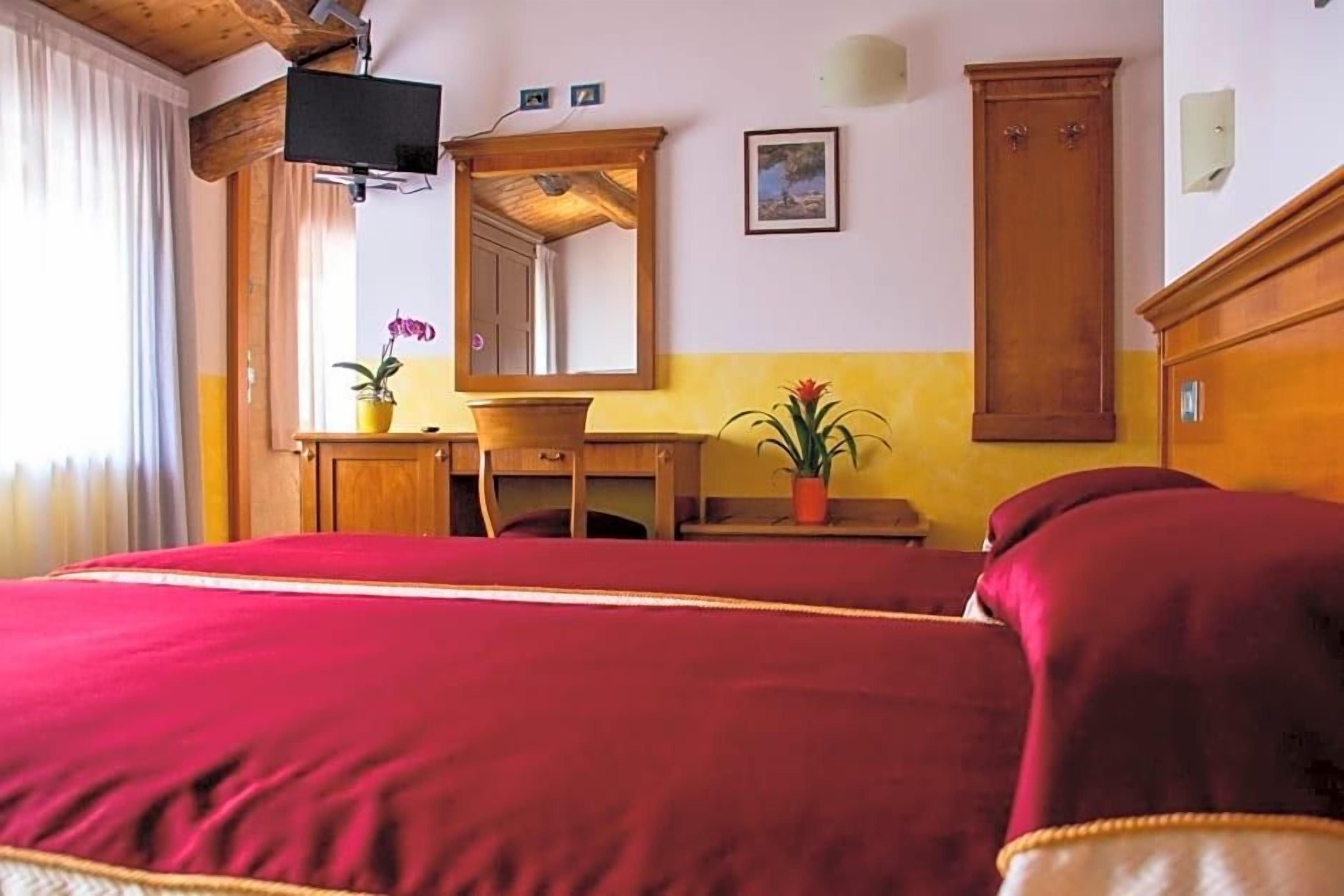 Ein Hotelzimmer mit einem großen Bett, einem Holztisch, einem Spiegel und einem Kleiderschrank.