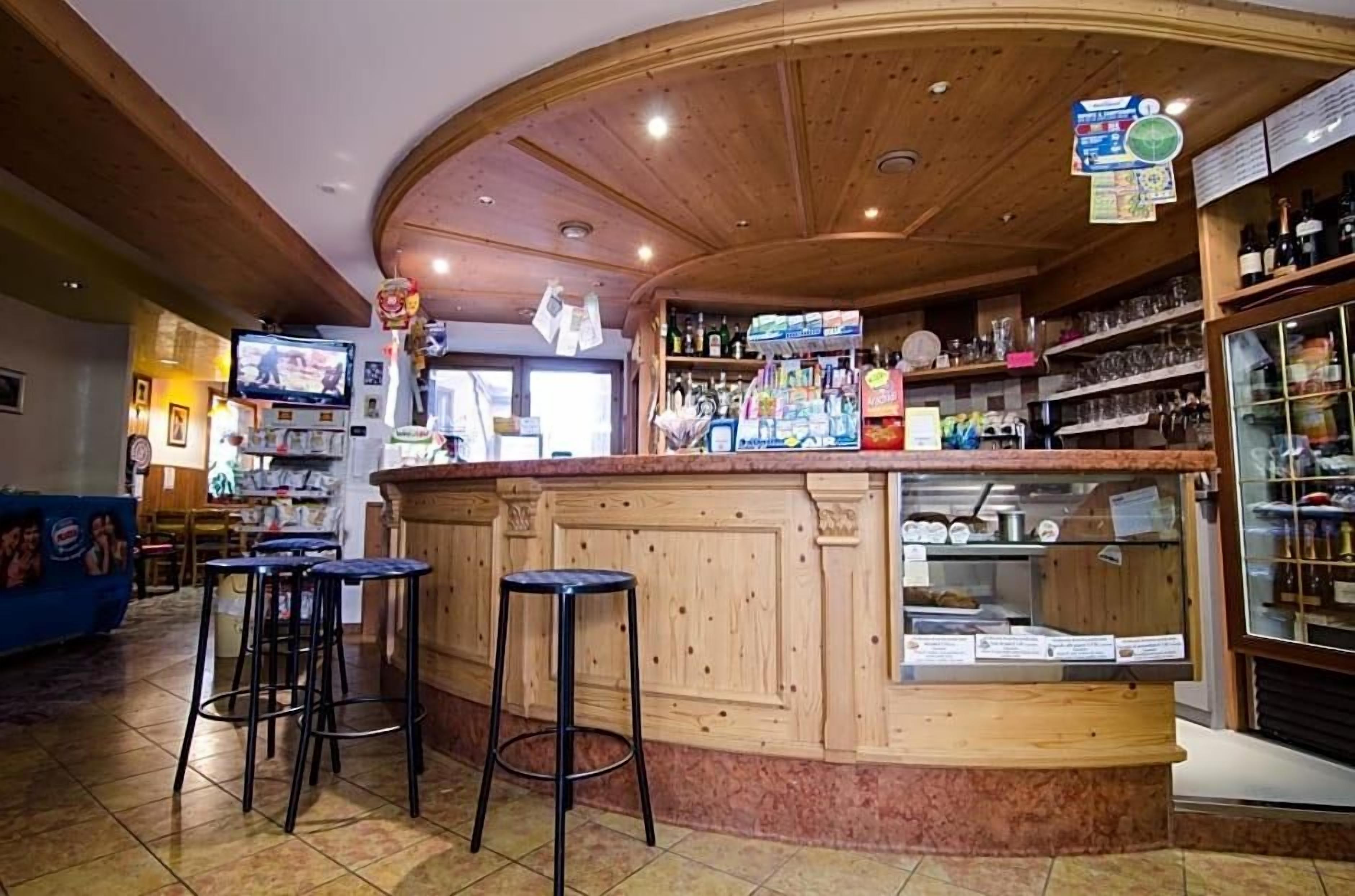 Un espace bar avec des tabourets de bar en bois, un comptoir et des étagères remplies de bouteilles et de verres.